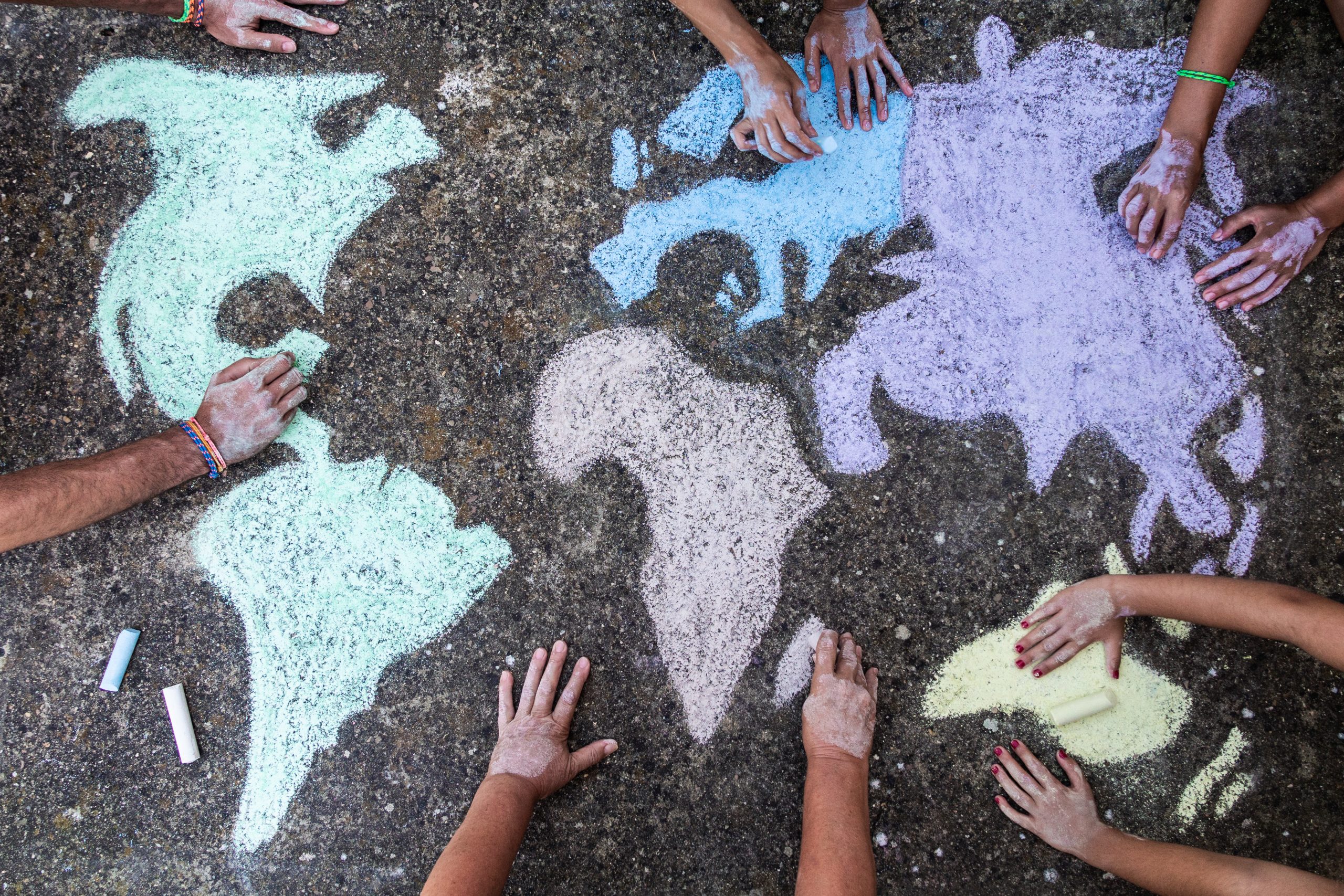 manos de niños y niñas dibujando el mundo